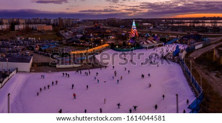 People ice skating during sunset. Beautiful ice skating park near Christmas tree in Riga, Latvia.