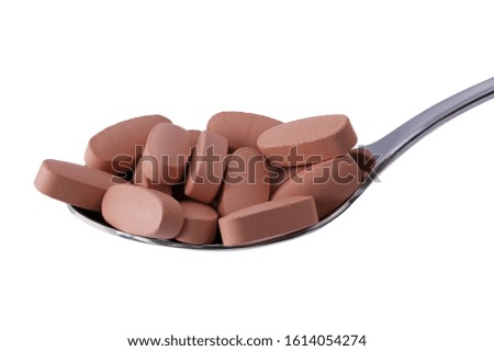 Vitamin pills on tablespoon isolated on white. Macro photography, food supplements. Concept for diet, health and nutrition.