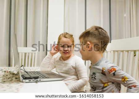 Brother and sister using laptop computer at home