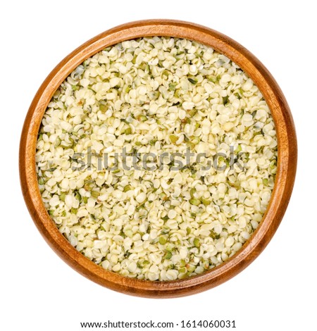 Hulled hemp seeds in wooden bowl. Raw and edible hempseeds. Small nuts of cannabis sativa. A mix of different hemp varieties. Closeup, from above, on white background, isolated macro food photo. Royalty-Free Stock Photo #1614060031
