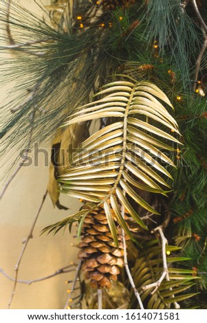 Stylish modern Christmas decorations with golden leaves and cones on fir branches.