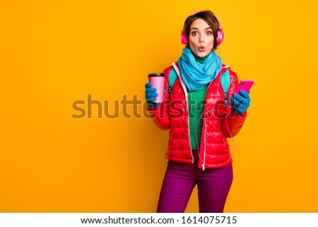 Photo of funny blogger lady open mouth hold telephone listen earphones youth music drink coffee wear casual red coat blue scarf gloves pants isolated yellow color background