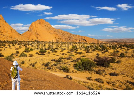 Picturesque stones in the Namib desert. Slender woman takes pictures of a beautiful landscape. Travel to Africa. The concept of active, extreme and photo-tourism
