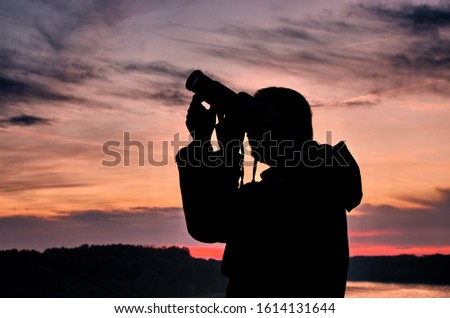 Silhouette of photographer taking picture during sunset .Silhouette of man photographer with camera at beautiful sunset.