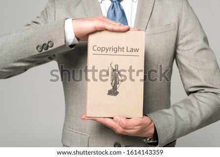cropped view of lawyer holding book with copyright law title isolated on grey