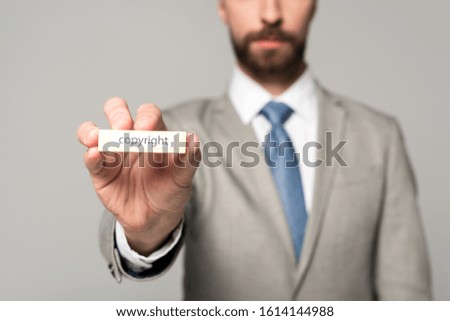 partial view of businessman showing wooden block with word copyright isolated on grey