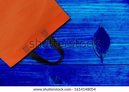 Reusable orange bag on blue wooden background, plastic waste reduction concept 