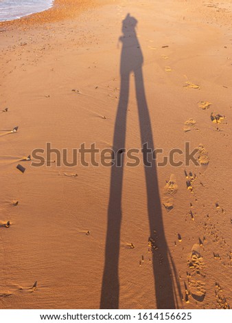 abstract picture with long human shadow, sea shore sand