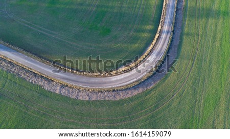 Curvy road between 2 fields photographed from above