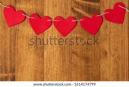 Bright red hearts hang on a rope on a wooden background, flat lay, top view, copy space. Background with red hearts for Valentine's day, wedding, holiday. Love and romance background. Royalty-Free Stock Photo #1614174799
