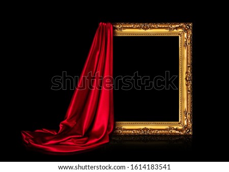 The wooden frame for the picture is covered with a silk red cloth isolated on a black background. Antique golden frame.