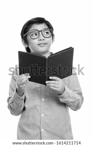 Cute Japanese boy wearing eyeglasses while holding book and thinking