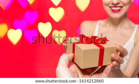Lovers give each other gifts concept. Two exchange presents over red backround with hearts bokeh