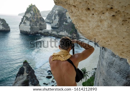 
Nature photographer on cliff taking picture of landscape awaking. Secret beach located in Nusa Penida, southeast of Bali Island, Indonesia. Wonderful seashore cliffs meet the great blue.