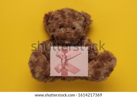 Teddy bear and gift box on yellow background. Christmas, birthday concept. Top view