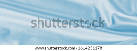 Light blue silk background with folds.  Abstract texture of rippled satin surface, long banner