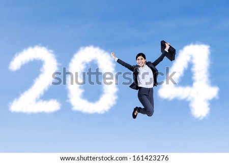 Happy businesswoman jumping with 2014 by clouds