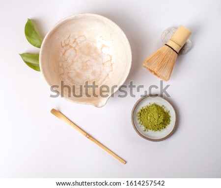 White ceramic spoon with tea of a match on a light gray background. Matcha green tea in powder