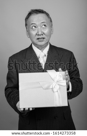 Portrait of mature Asian businessman against gray background