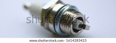 Close-up of automobile detail on white blurred background. New sparking-plug for vehicles. Replacement of auto parts. Repair and maintenance of transport