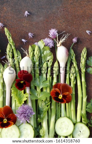 Spring still life of vegetables and flowers. Asparagus, chives, parsley and cilantro. Rusty metal background, selective focus.

