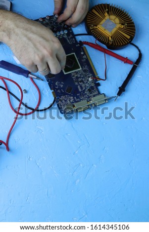 Male hands repair an electronic device using Multimetr, measuring the voltage of the computer motherboard with a digital multimeter. 
Copy space - the concept of servicing computer equipment, laptops 