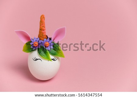 cute spring Easter card with an unicorn egg with a rim of spring flowers and horn  with copy space on a pastel pink background