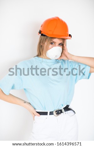 girl in a protective helmet and respirator looks into the camera on a white background