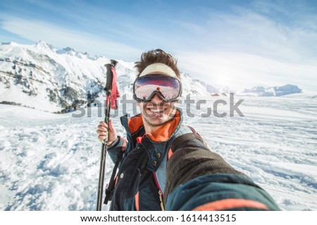Skier man is taking a selfie on a snowy mountain at winter