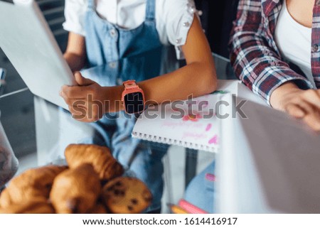 Children hands doing homework using digital tablet, close up photo, pink smart watches at kid hand.