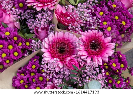 Bouquets of purple and pink flowers wrapped in paper from above. Beautiful background of colorful flowers bouqets. Close up photo.
