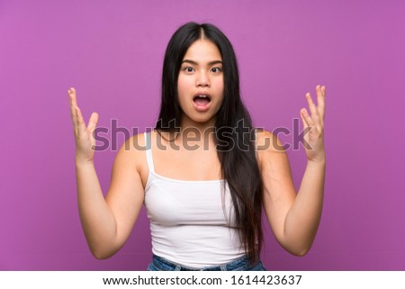 Young teenager Asian girl over isolated purple background with surprise facial expression
