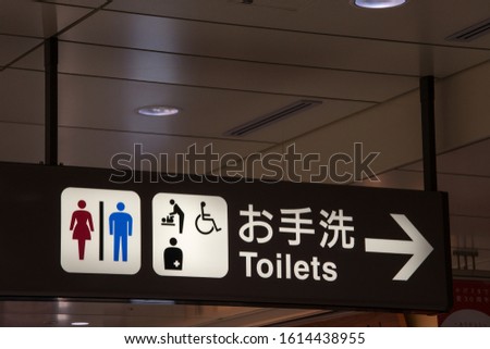 Male and female toilet sign with arrow in Japan.