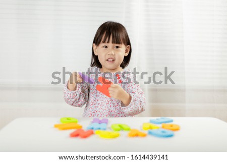 toddler girl learning alphabet letter at home against white background