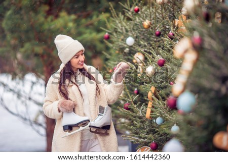 Happy young woman with skates ready to skate on ice rink