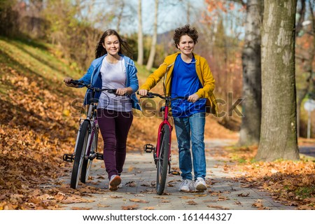 Girl and woman riding bikes in city park
