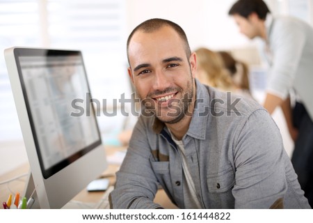 Cheerful guy sitting in front of desktop computer Royalty-Free Stock Photo #161444822