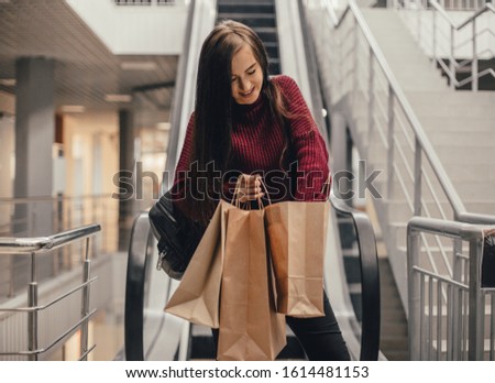 Young pretty woman blogger with smartphone, cup of coffee and shopping bags in city mall