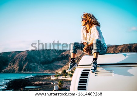 Travel concept with independent people enjoyig the outdoor leisure activity and wanderlust life lifestyle - woman sit down on the roof of a old nice vintage camper van Royalty-Free Stock Photo #1614489268