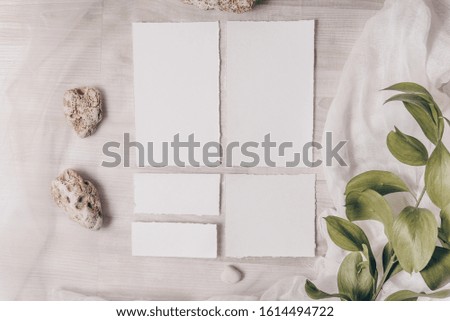 Feminine wedding, birthday mockup scene, greeting card, presentation. Watercolor textured paper greeting cards, plate, stones, green leaves. White textile on a table background. Flat lay, top view