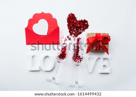
Glasses for champagne, gift, love message and the word love on a white background top view. Valentine's day background.