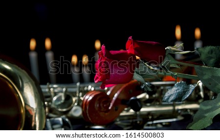 red rose in black background.smoke and candles .romantic flower saint valentines day.death and funeral flowers for musician violin and saxophone