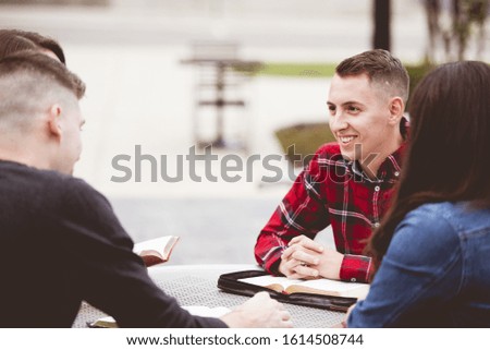 A group of people sitting around a table by the calm lake