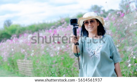 Beautiful of Asia women blogging in the flowers garden 