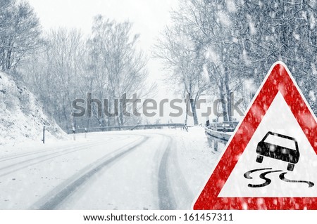 Snowy road with traffic sign  Sudden and heavy snowfall on a country road. Driving on it becomes dangerous Ã¢Â?Â¦  Royalty-Free Stock Photo #161457311