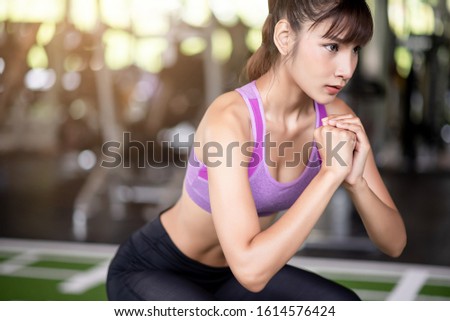 Beautiful healthy asian woman squating in the gym.
 Royalty-Free Stock Photo #1614576424