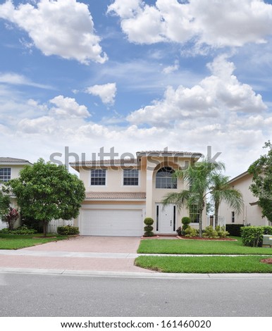 Suburban Home Brick Driveway Landscaped Lawn Palm Trees Blue Sky Clouds USA Residential Neighborhood 