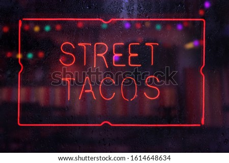 Neon Street Tacos Sign in Wet Window