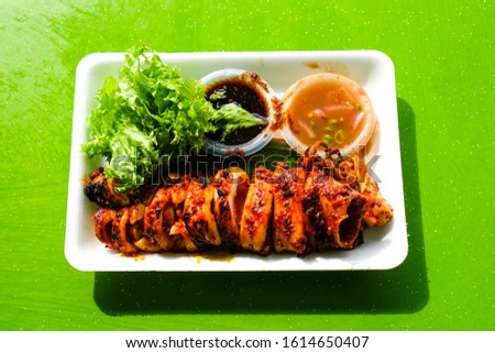 A picture of the best grilled squid set on white plate with harsh shadow in Port Dickson