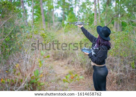 A girl piloting a drone in the forest 